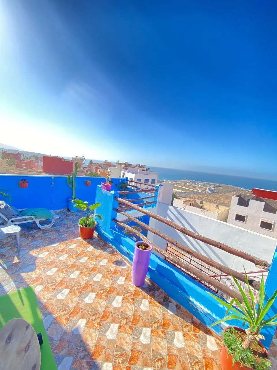 Blue rooftop terrace with plants, tiled flooring and a view towards the Atlantic