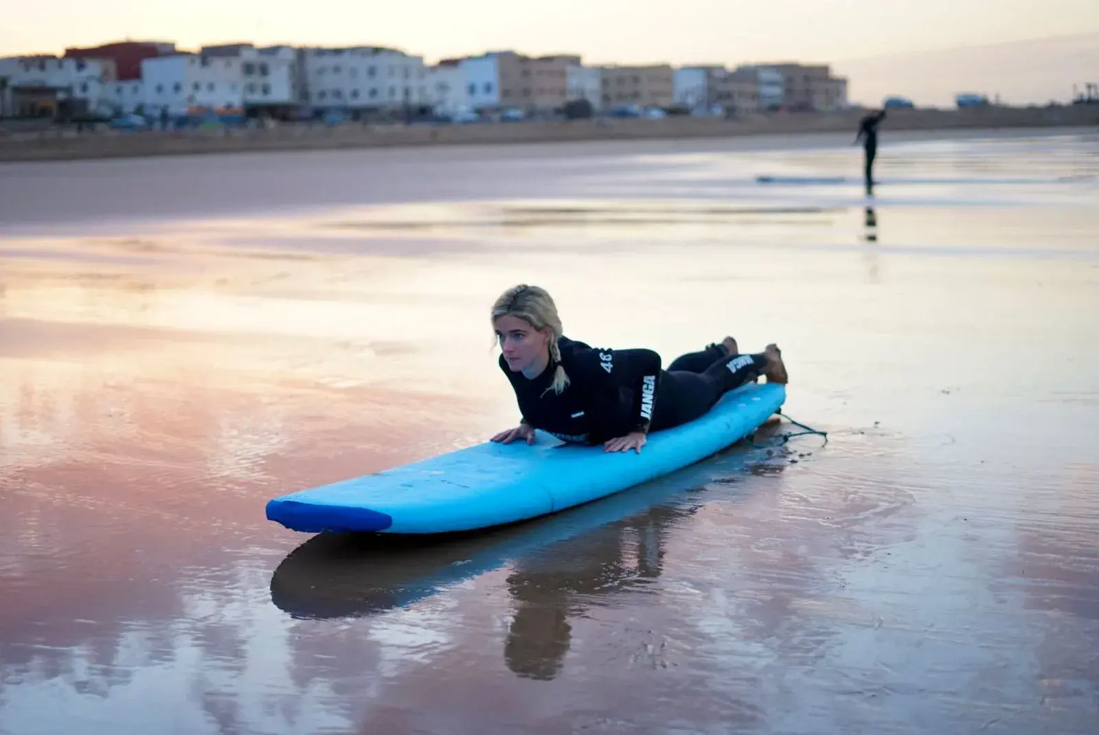 Surfer practicing on a blue surfboard at the water’s edge